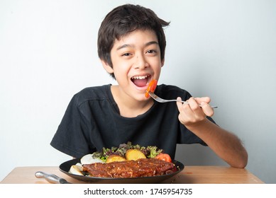 Little Boy Teenager Eating Tomato With Salad For His Meal