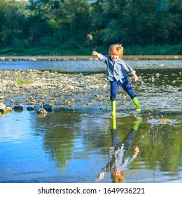 Little Boy Throw Stones At The Stony River. Beautiful Kids Girl Throws A Rock At The River. Skipping Rocks. Boy Traveling Away From Home. Adventure And Vacations Children Concept