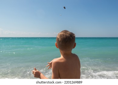 Little Boy Throwing Pebbles Into The Sea