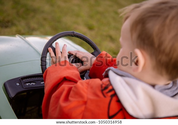 Little boy in toy car presses\
horn
