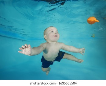 Little Boy With Toy Learns To Dive Underwater In A Swimming Pool
