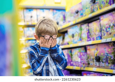 The little boy in the toy store is upset. The kid covered his eyes with his hands, crying. Child's tears in toy shop. 