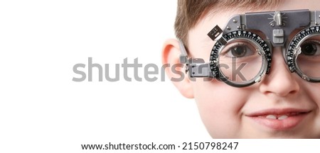 Little boy with trial frame undergoing eye test on white background with space for text, closeup