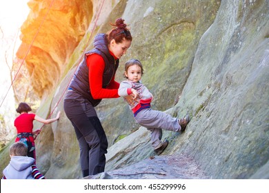 A Little Boy Tries Climbing With Mom On The Rocks.