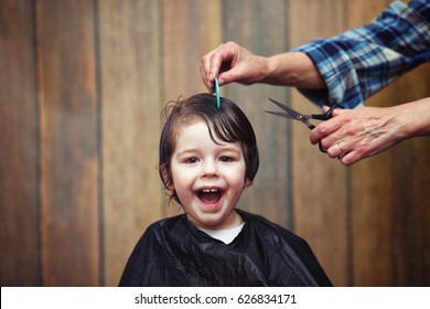 Een kleine jongen is getrimd in de felle emoties van de kapper op zijn gezicht