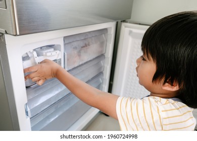 Little Boy Trying To Get Some Ice From The Ice Maker In The Refrigerator