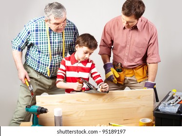 Little Boy Trying His Best In A Woodshop Being Looked After By His Dad And Grandfather