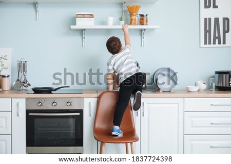 Little boy trying to reach out for pasta at home