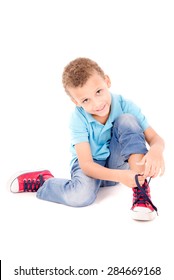 Little Boy Tying His Shoes Isolated In White