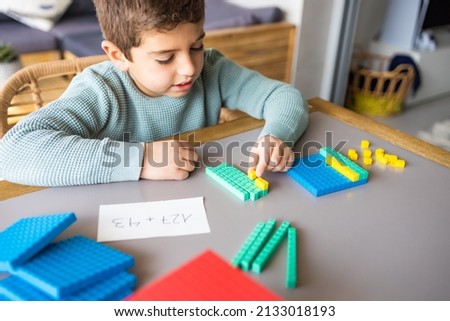 Little boy using the base 10 method to do addition at home