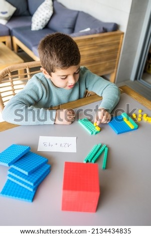 Little boy using the base 10 method to do addition at home
