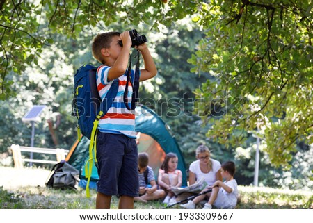 Little boy using binoculars to watch birds.He standing in front of his friends and teacher.