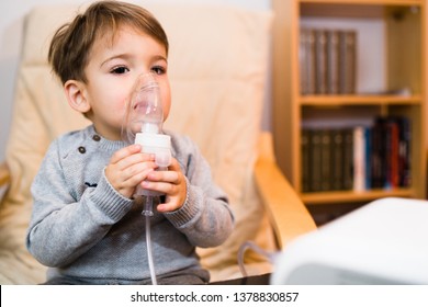 Little boy using steam inhaler nebulizer mask inhalation at home. Medical procedures vapor medication treatment asthma pneumonia bronchitis coughing
