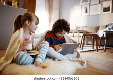 Little boy using tablet with his sister on living room floor - Powered by Shutterstock