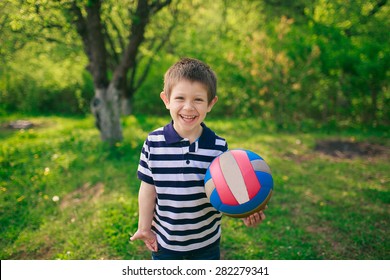 Little Boy Walking At Night In The Park. Keep The Ball