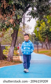 A Little Boy Walking On The Park Path