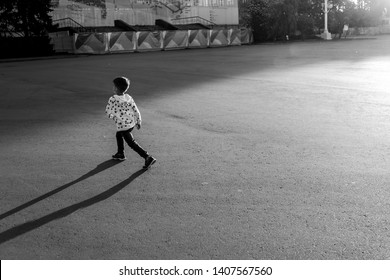 a little boy is walking on the road at sunset, casting a shadow