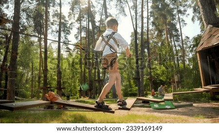 Little boy walking over wobbly rope bridge and holding tight safety rope. Active childhood, healthy lifestyle, kids playing outdoors, children in nature Stock photo © 
