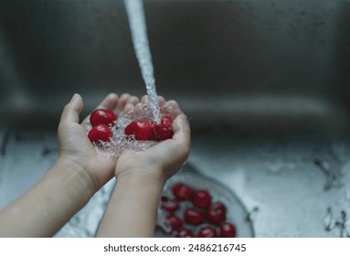 little boy is washing red cherries in the sink - Powered by Shutterstock