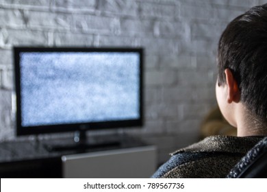 Little Boy Watching Lcd TV In A Dark Room With Loft Style Brick Walls, Backside View.