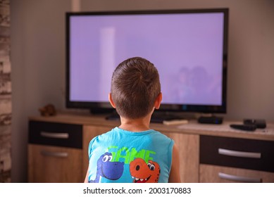 A Little Boy Watching TV At Home. View From Behind Sofa