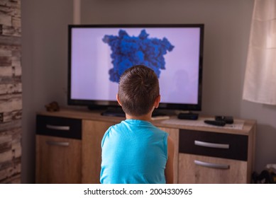 A Little Boy Watching TV At Home. View From Behind Sofa