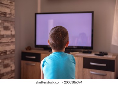 A Little Boy Watching TV At Home. View From Behind Sofa