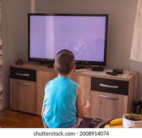 A Little Boy Watching TV At Home. View From Behind Sofa