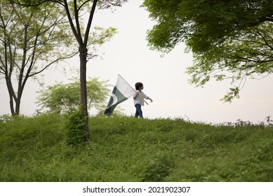 Little Boy Waving Pakistan Flag On The Mountain, Celebration Pakistan Independence Day.