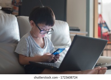 little boy Wear glass using laptop on sofa in home, work from home - Powered by Shutterstock