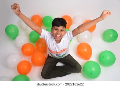 Little boy wearing India Tshirt, raising his hands and Decorated Tricolour balloons on both sides. Celebrating Independence day or Republic day.