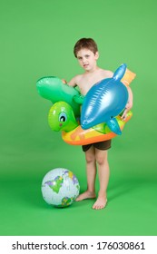 A Little Boy Wearing An Inner Tube Holding Inflatable Animals Next To An Inflatable Globe.