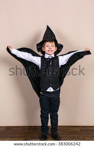 Little boy wearing school uniform and magic cloak with hat. Boy is happy and smiling