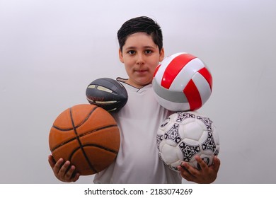 A little boy wearing a white sports shirt holding soccer, football, basketball and volleyball balls. Boy with sports balls on a white isolated background. - Powered by Shutterstock