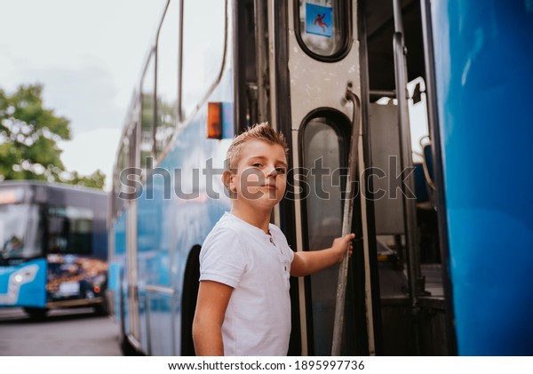 A little boy in a white T-shirt gets on a bus, a
public transport concept