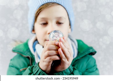 little boy in winter clothes with small snow globe - Powered by Shutterstock