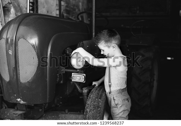 a little boy\
with a wrench repairs a\
tractor