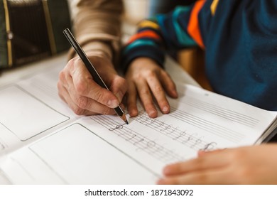 The little boy writes musical notes and violin key with the help of his father at home. - Powered by Shutterstock