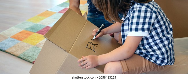 Little Boy Writing His Name In A Moving Box With His Father