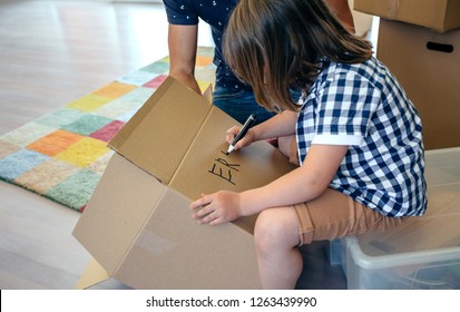 Little Boy Writing His Name In A Moving Box With His Father