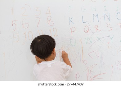 Little Boy Writing  On Wall Background