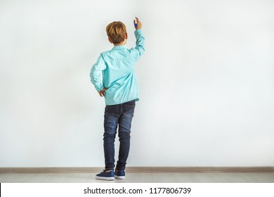 The Little Boy Writing On The White Wall