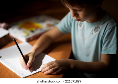 A Little Boy Writing With A Pencil Close Up