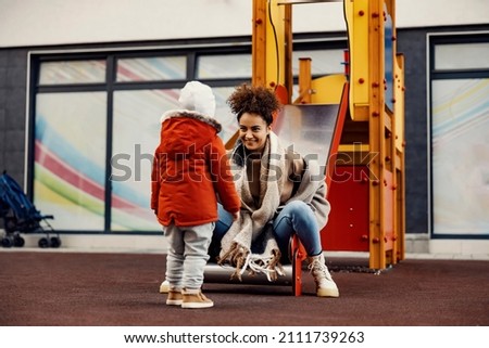 A little boy and a young woman, nanny, having fun at the outdoor playground.