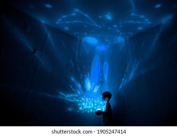 Little Boyl In His Room With Night Light Projecting Stars On Room Ceiling. Children Read Before Bedtime.