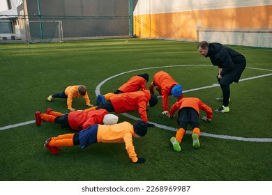 Little boys, children, football players training with professional coach outdoors on sport field. Doing push up exercises. Concept of sport, childhood, active lifestyle, hobby, sport club - Powered by Shutterstock