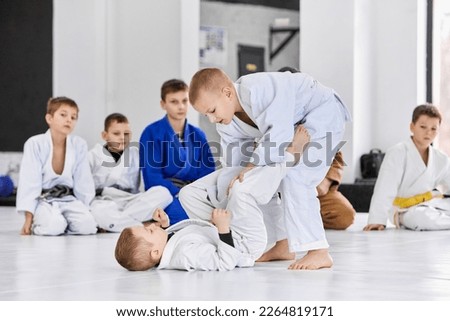 Little boys, children in white kimono training judo, jiu-jitsu indoors. Professional sports club for kids. Concept of martial arts, combat sport, sport education, childhood, hobby