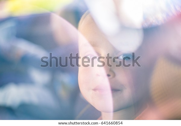Little\
boy\'s face behind the window with\
reflections