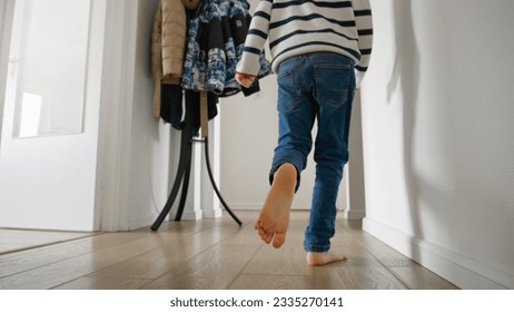 Little boy's feet running on wooden floor in long corridor at home. Concept of happy childhood, playing at home, child development - Powered by Shutterstock