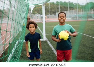 Little Boys Playing Football. African American Schoolboy At Stadium. Young Kids Running Outside. Happy Black Children Practicing Soccer. Training At Field With Ball. Exercise And Healthy Lifestyle